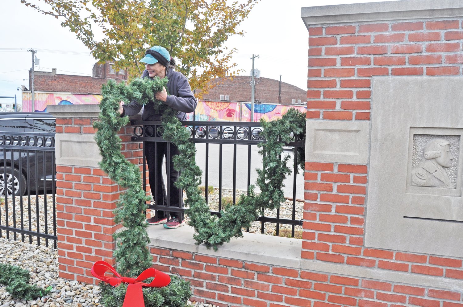 Marie Stocks wraps garland around the fence at the Montgomery County Courthouse Tuesday.